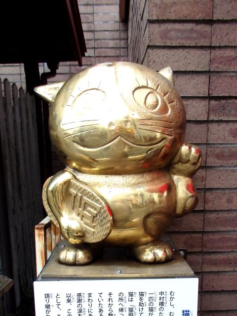 小判を脇に抱えた、黄金の猫飛像。